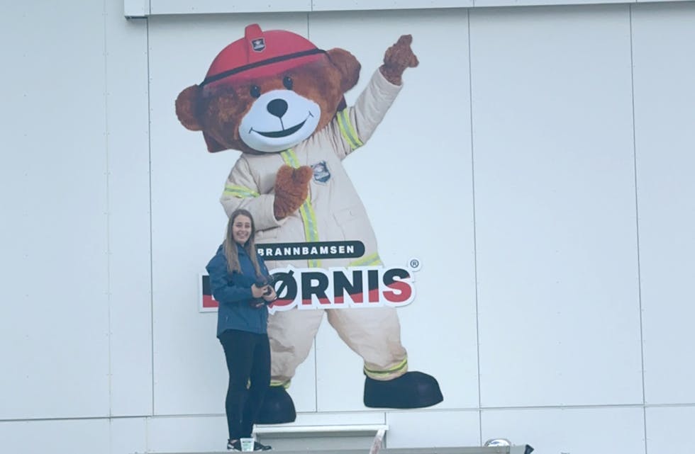 KLARGJER DEN NYE HEIMEN: Elise Orheim Bakkebø er røykdykkar i brannkorpset. Her har ho fått oppgåva med å henge opp skiltet til Bjørnis på brannstasjonen på Fiskå. Vanylven vert den minste kommunen Bjørnis bur i, med det nest største Bjørnis-skiltet i Noreg, kan brannsjefen opplyse om.